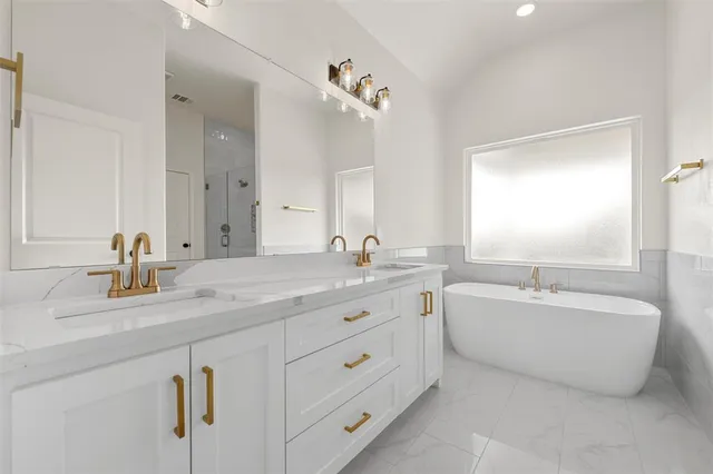 a spacious bathroom with a double vanity sink mirror and bathtub