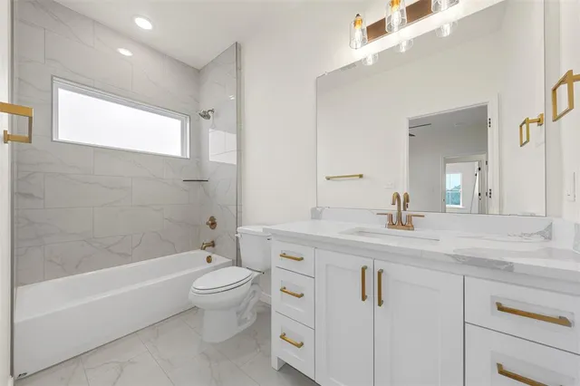 a spacious bathroom with a granite countertop toilet a sink and a bathtub