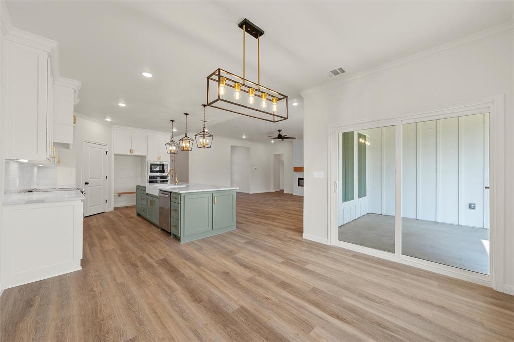 920 Gallant Fox Hewitt, TX 76643 - Photo 34 of 36 a large kitchen with kitchen island a stove a sink dishwasher and white cabinets with wooden floor