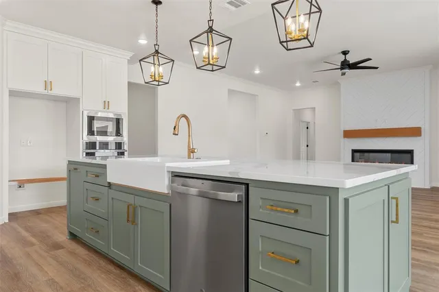 a large kitchen with kitchen island a stove a sink dishwasher and white cabinets with wooden floor