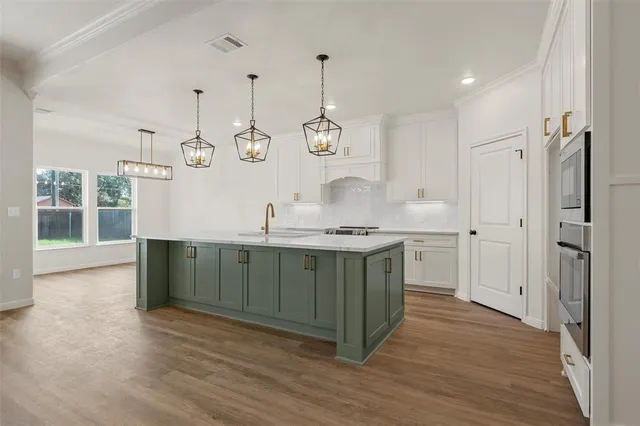 a kitchen with stainless steel appliances granite countertop a sink cabinets and wooden floor