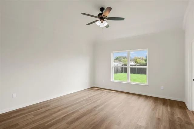 an empty room with wooden floor fan and windows