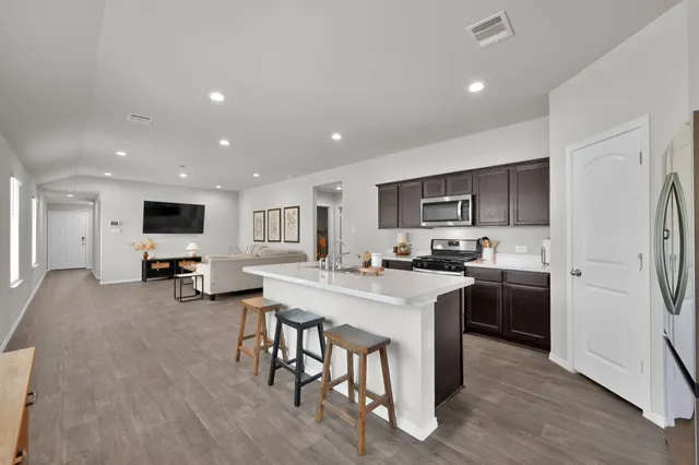 a kitchen with stainless steel appliances a stove a sink a refrigerator cabinets and a table