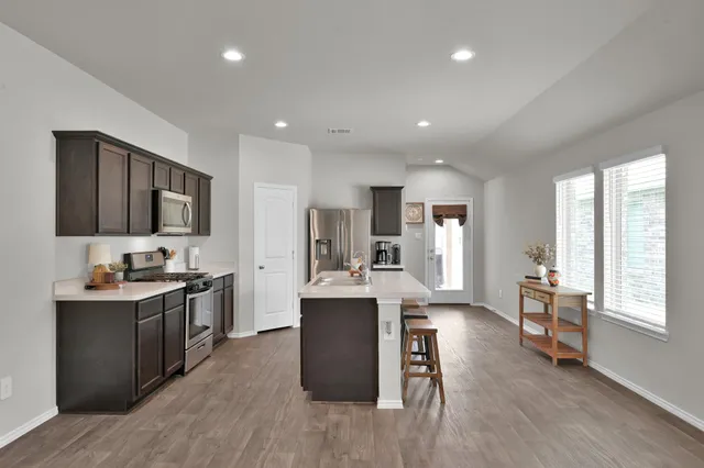 a kitchen with stainless steel appliances granite countertop sink stove refrigerator and wooden floor