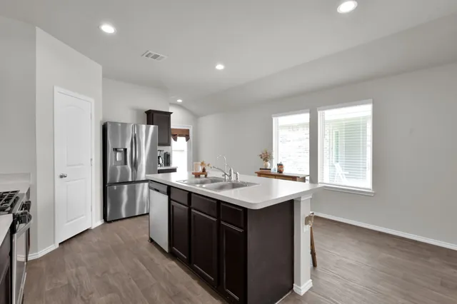 a kitchen with refrigerator sink and wooden floor