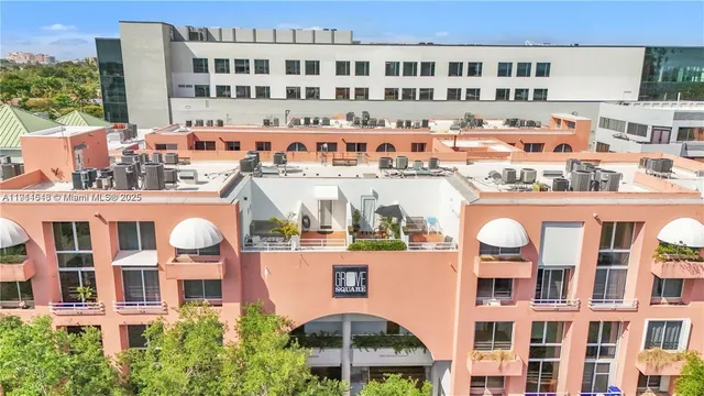 a front view of a building with glass windows and plants