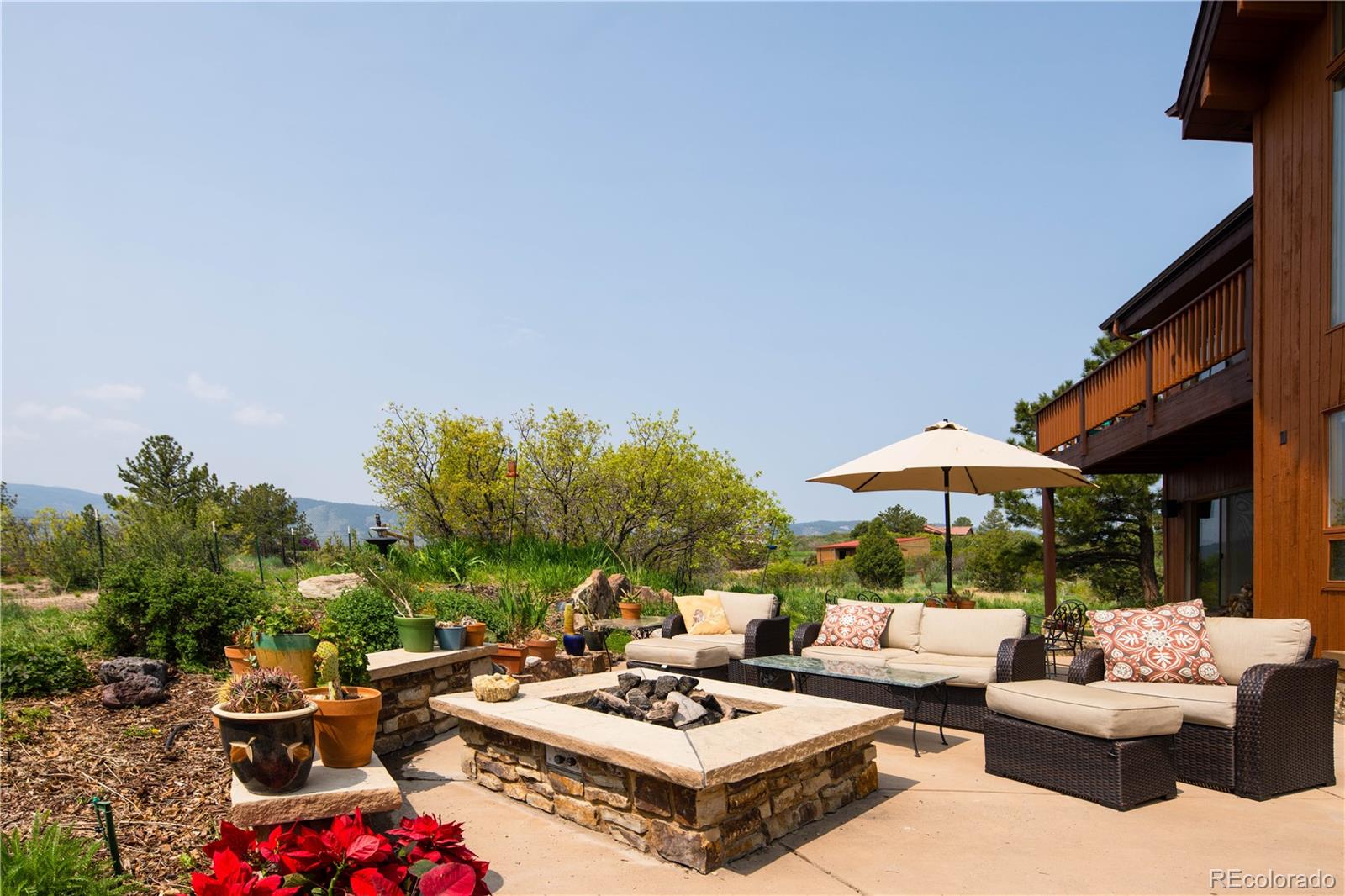 729 Coronado Drive Sedalia, CO 80135 - Photo 11 of 28 a view of a patio with dining table and chairs under an umbrella with a small garden