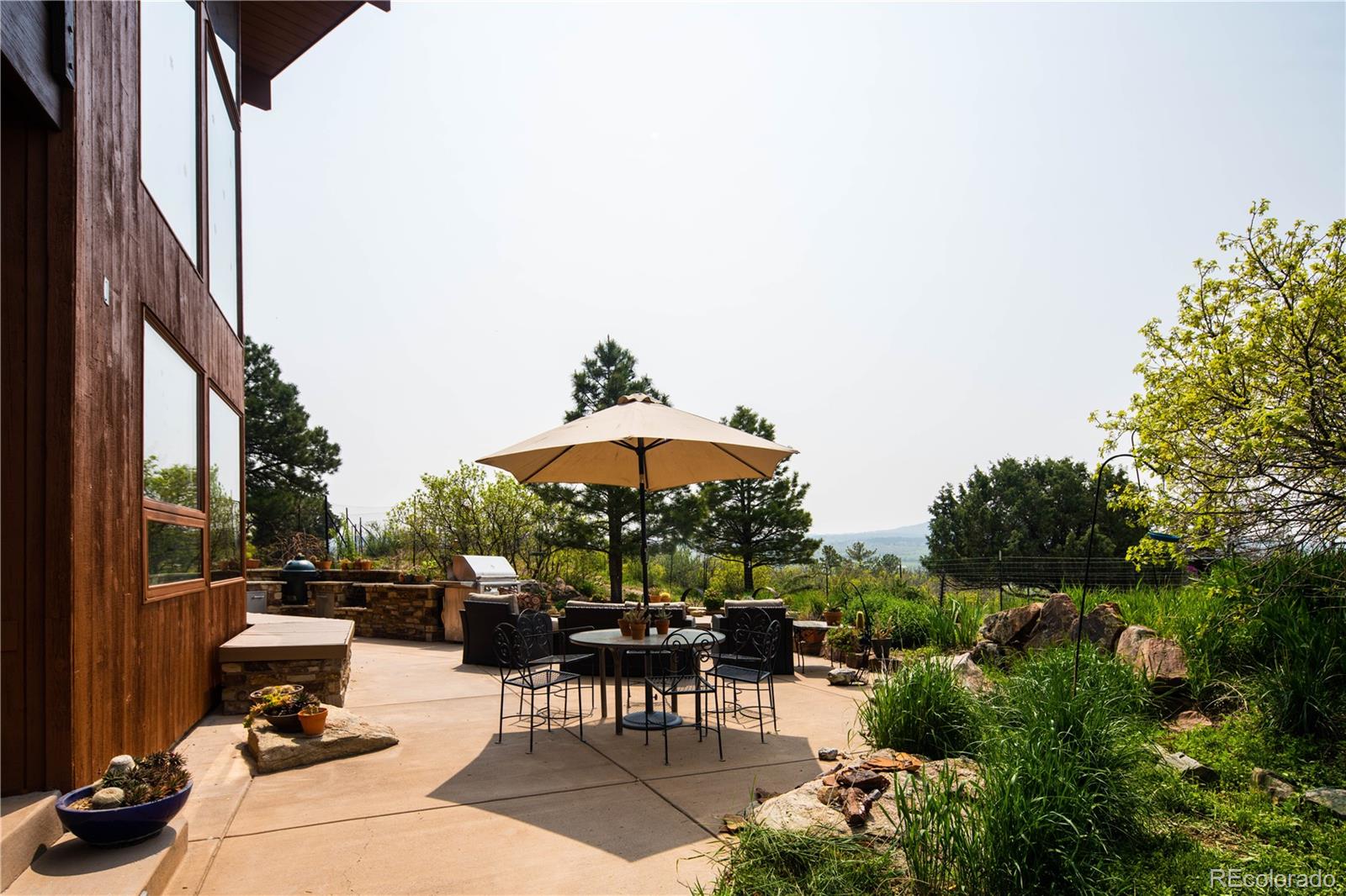 729 Coronado Drive Sedalia, CO 80135 - Photo 14 of 28 a view of a patio with a table and chairs under an umbrella with a small garden