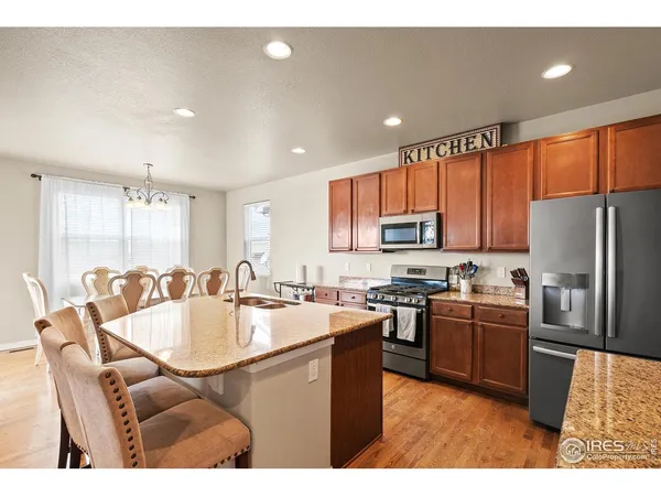 a kitchen with stainless steel appliances granite countertop a refrigerator a stove a sink a dining table and chairs