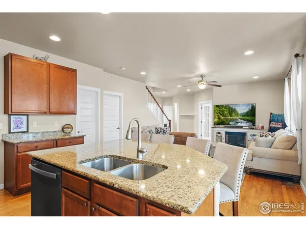 a kitchen with stainless steel appliances granite countertop a sink a stove and a living room view