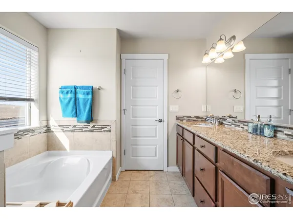 a bathroom with a tub a double vanity sink and a mirror