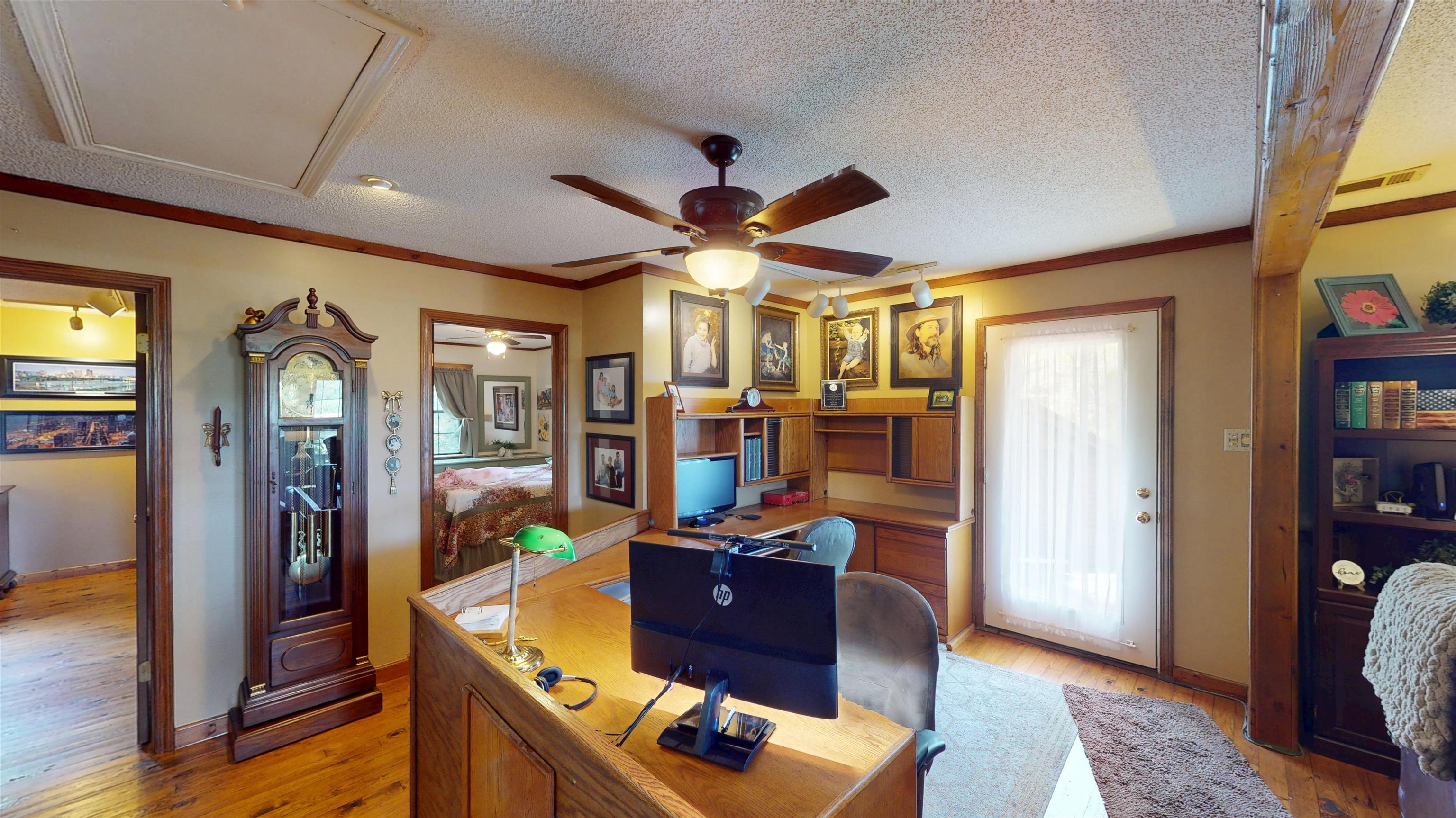 420 Joann Road Somerville, TN 38068 - Photo 9 of 40 Built-in wood shelving and desk system, wood-finish flooring, ceiling fan with integrated lighting, and a white paneled door