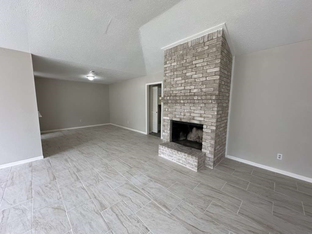 11807 South Youngwood Lane Houston, TX 77043 - Photo 4 of 13 a view of an empty room with wooden floor fireplace and a window