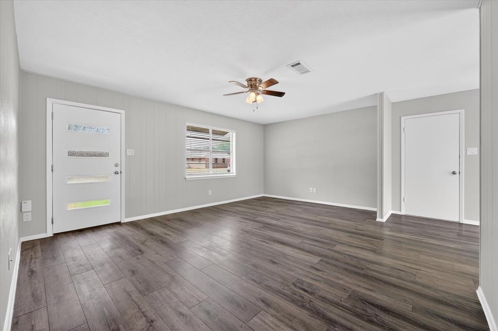 an empty room with wooden floor and windows