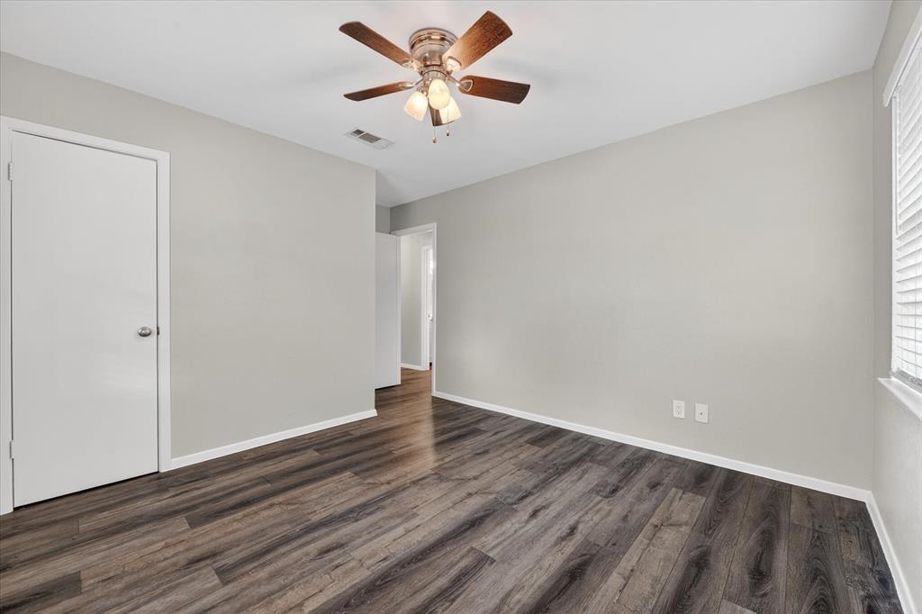 205 Wayne Street Sanger, TX 76266 - Photo 16 of 29 an empty room with wooden floor and a ceiling fan