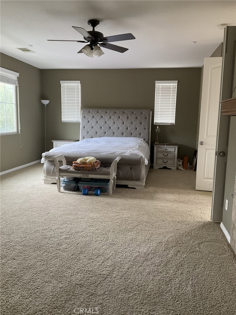 9503 Orleans Lane Riverside, CA 92508 - Photo 16 of 28 a spacious bedroom with a bed and a chandelier