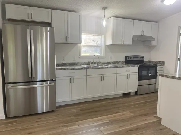 a kitchen with stainless steel appliances granite countertop a refrigerator sink and white cabinets