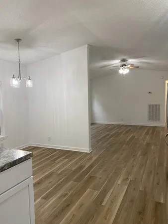 an empty room with wooden floor fan and window