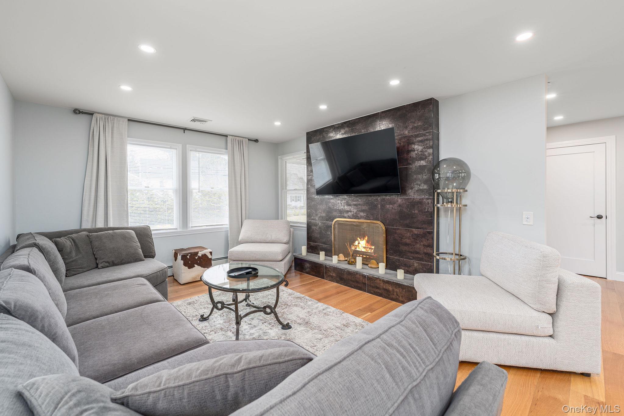 10940 Main Road East Marion, NY 11939 - Photo 11 of 38 a living room with furniture a flat screen tv and a fireplace