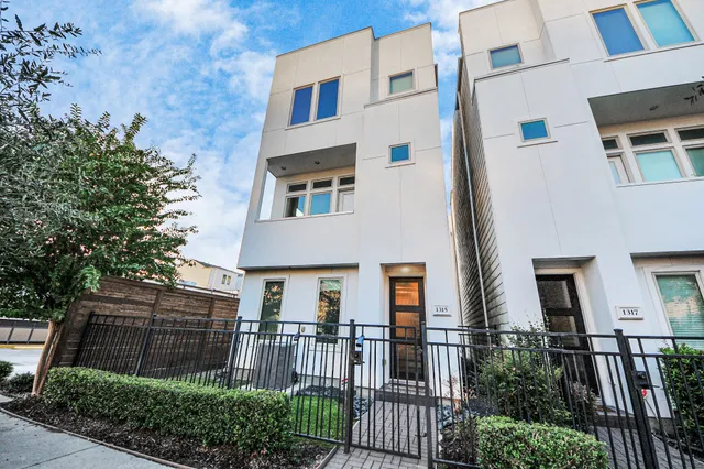 a view of a brick house with many windows next to a yard