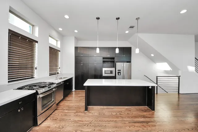 a large kitchen with stainless steel appliances a large counter top