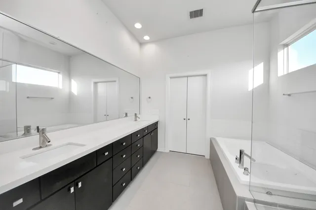 a spacious bathroom with a double vanity sink a mirror and a bathtub