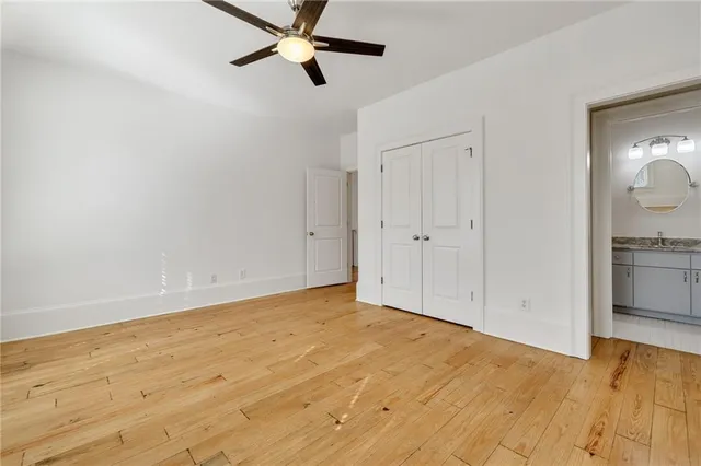 a view of empty room with wooden floor and ceiling fan
