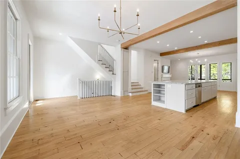 a view of an empty room and kitchen with sink