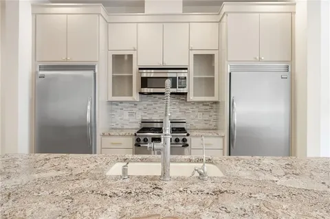 a kitchen with granite countertop a refrigerator and microwave