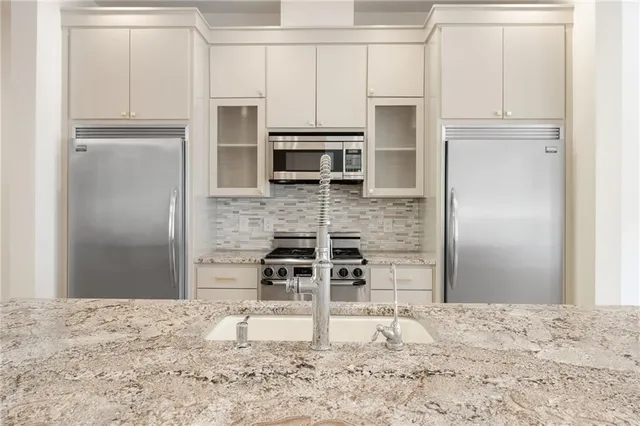 a kitchen with granite countertop a refrigerator and microwave