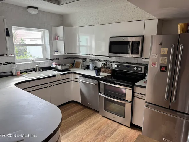 a kitchen with stainless steel appliances a stove a sink a microwave a refrigerator and wooden floor