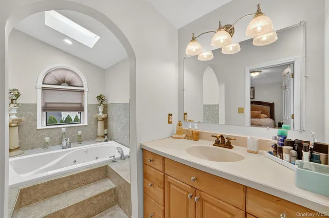 a spacious bathroom with a granite countertop sink a large mirror and a bathtub with wooden floor