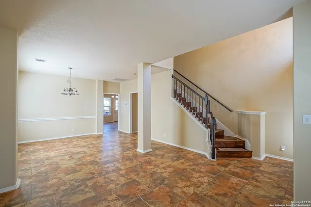 a view of an empty room with wooden floor and stairs