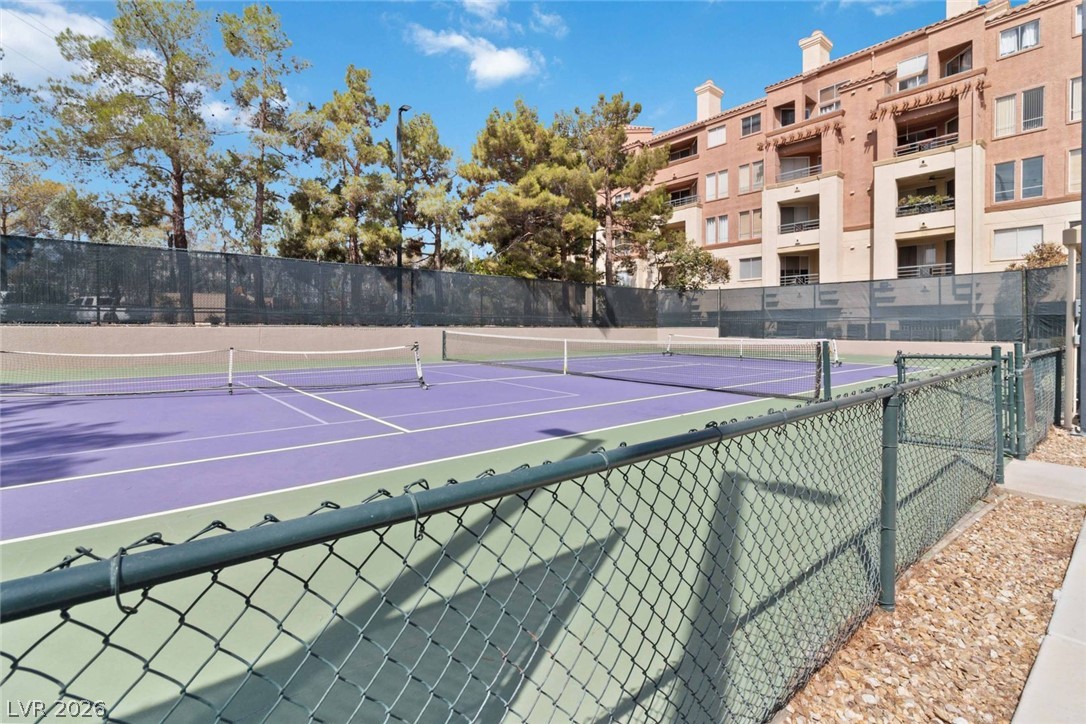 210 East Flamingo Road, Unit 208 Las Vegas, NV 89169 - Photo 42 of 42 Two vibrant tennis courts offer recreation against a backdrop of established trees and a multi-story building.