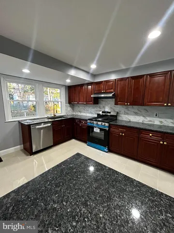 a kitchen with stainless steel appliances granite countertop a stove sink and cabinets