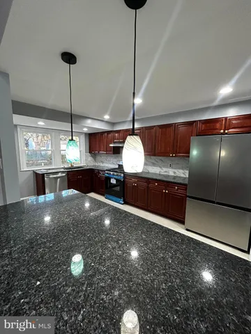 a kitchen with kitchen island a chandelier a stove and a counter top space