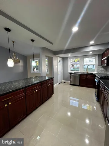 a large kitchen with kitchen island a sink stainless steel appliances and a chandelier