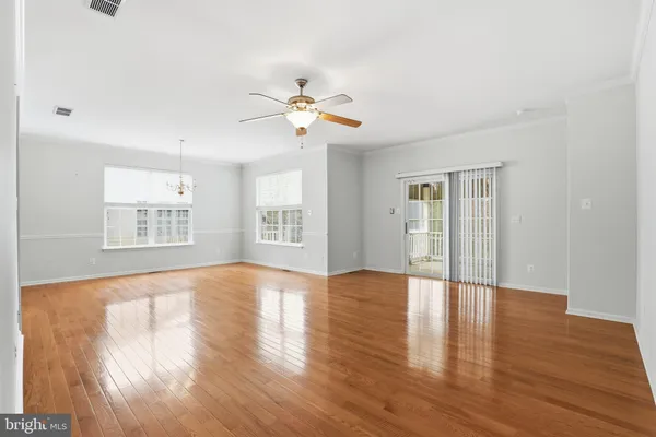 a view of an empty room with window and wooden floor