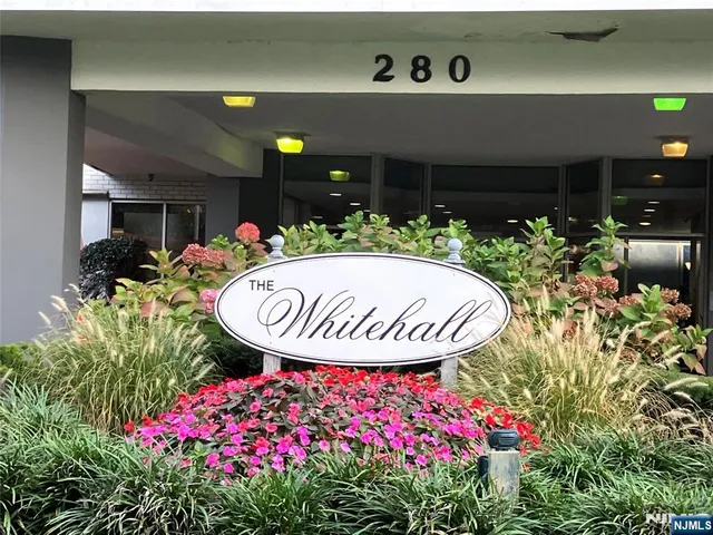 a front view of a house with a fountain and flowers