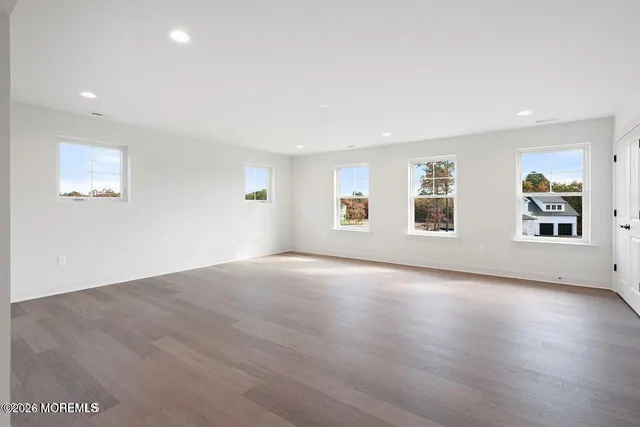 a view of an empty room with wooden floor and windows