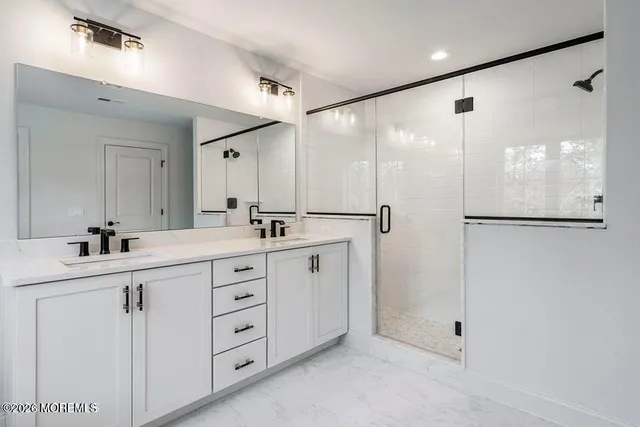 a spacious bathroom with a double vanity sink a large mirror a shower and vanity