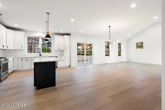 a large kitchen with stainless steel appliances kitchen island granite countertop a refrigerator a sink and white cabinets