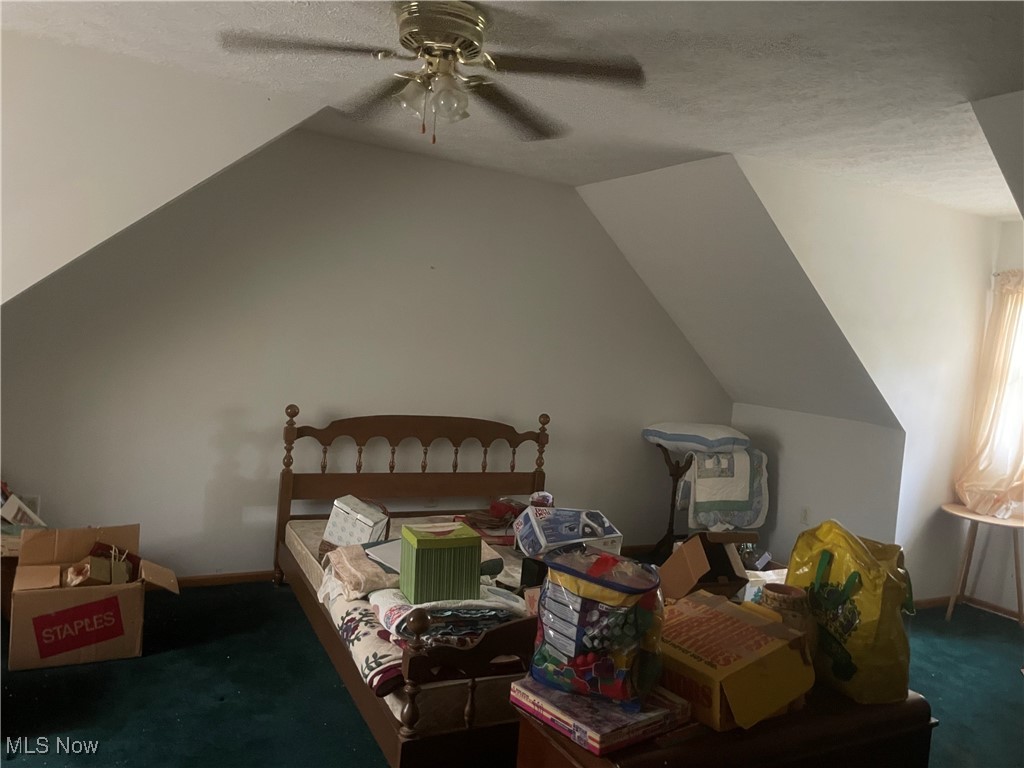 Bedroom featuring carpet flooring, vaulted ceiling, ceiling fan, a textured ceiling, and baseboards