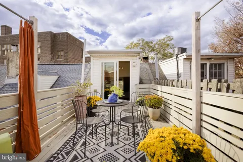 a balcony with table and chairs and potted plants