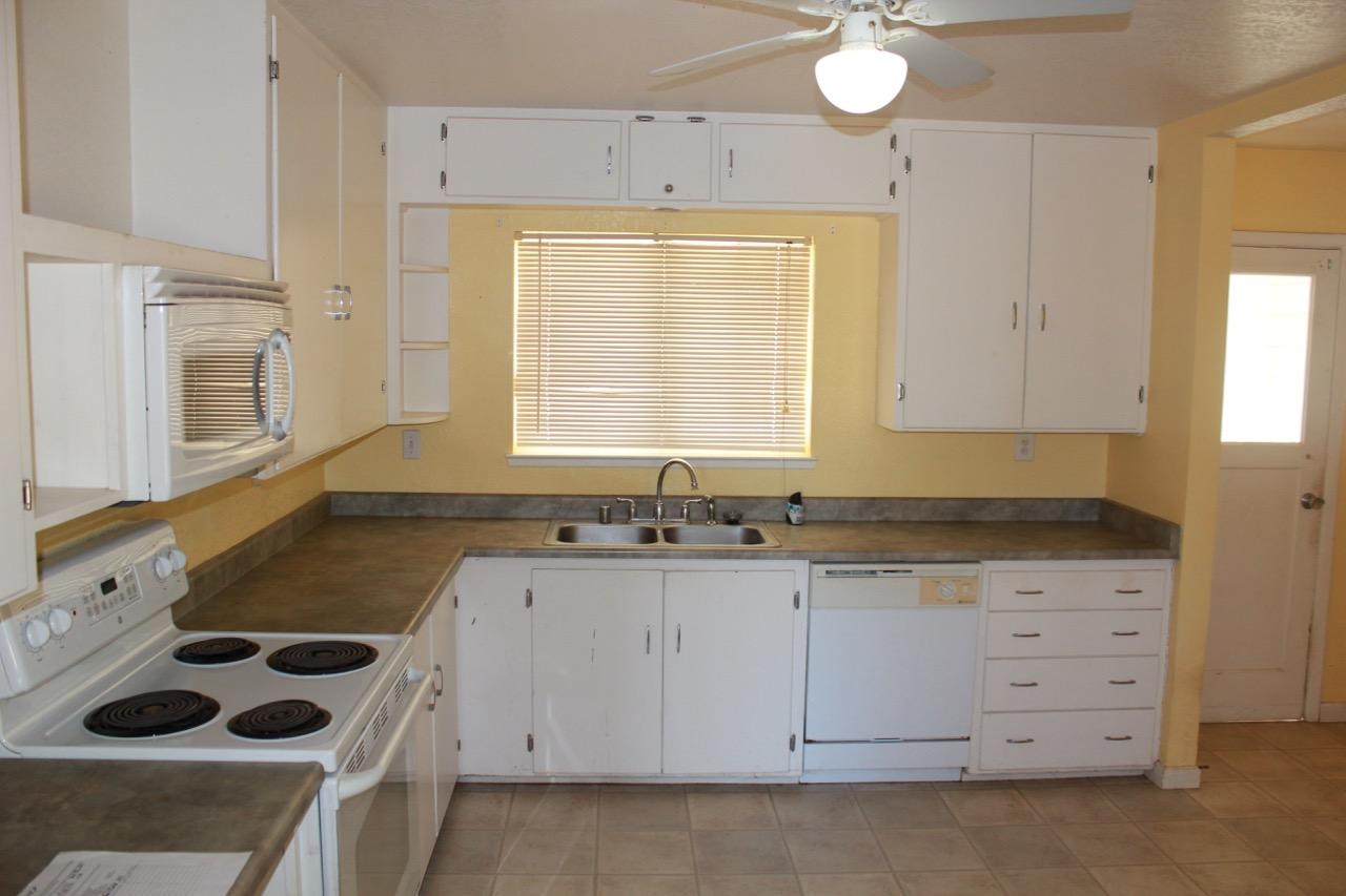 19819 Reeds Creek Road Red Bluff, CA 96080 - Photo 5 of 18 a kitchen with granite countertop a sink a stove and cabinets