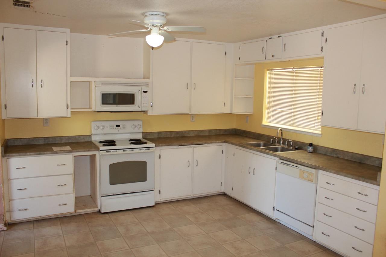 19819 Reeds Creek Road Red Bluff, CA 96080 - Photo 6 of 18 a kitchen with granite countertop white cabinets white stainless steel appliances and sink