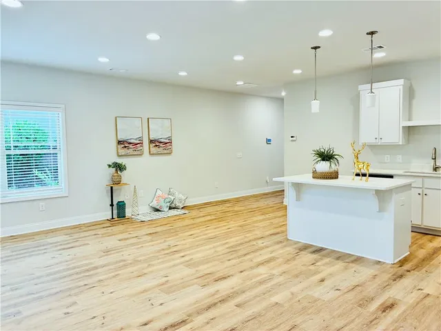 a room with kitchen island a sink wooden floor and window