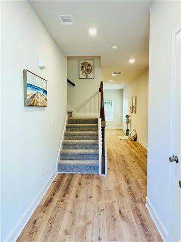 a view of a hallway with wooden floor and a bathroom