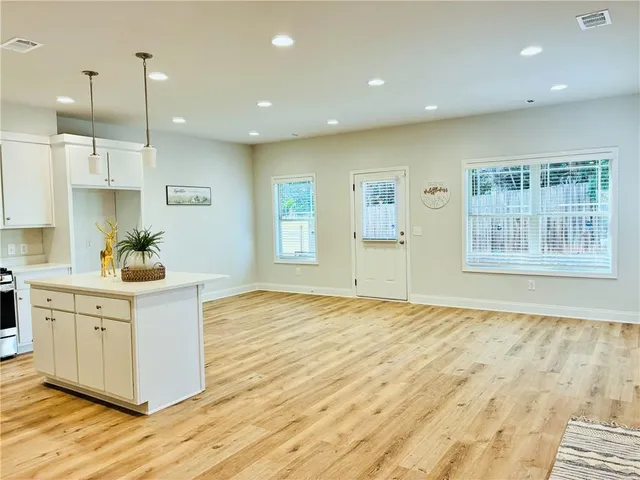 a large white kitchen with kitchen island white cabinets and wooden floor