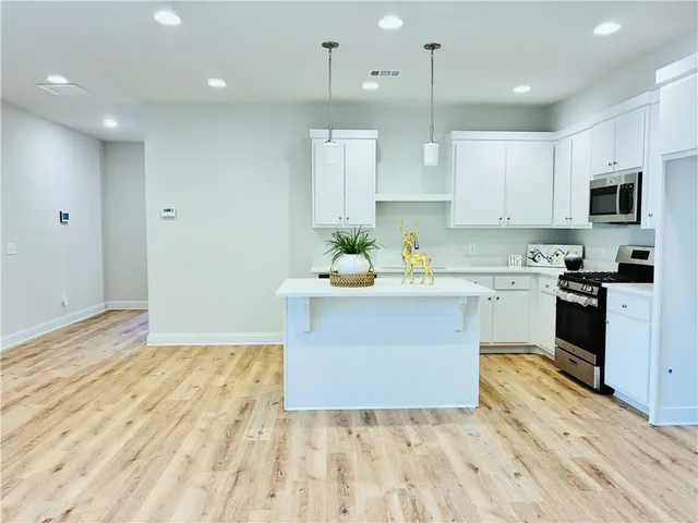 a large kitchen with stainless steel appliances kitchen island granite countertop a stove a sink dishwasher and a refrigerator with wooden floor